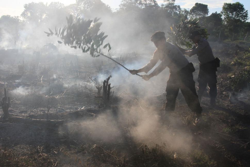 Personil Kepolisian Polres Aceh Barat bersama warga memadamkan api yang membakar lahan gambut dengan cara manual di Kawasan Desa Seuneubok, Kecamatan Johan Pahlawan, Aceh Barat, Aceh, Minggu (6/1). ANTARA FOTO/Syifa Yulinnas