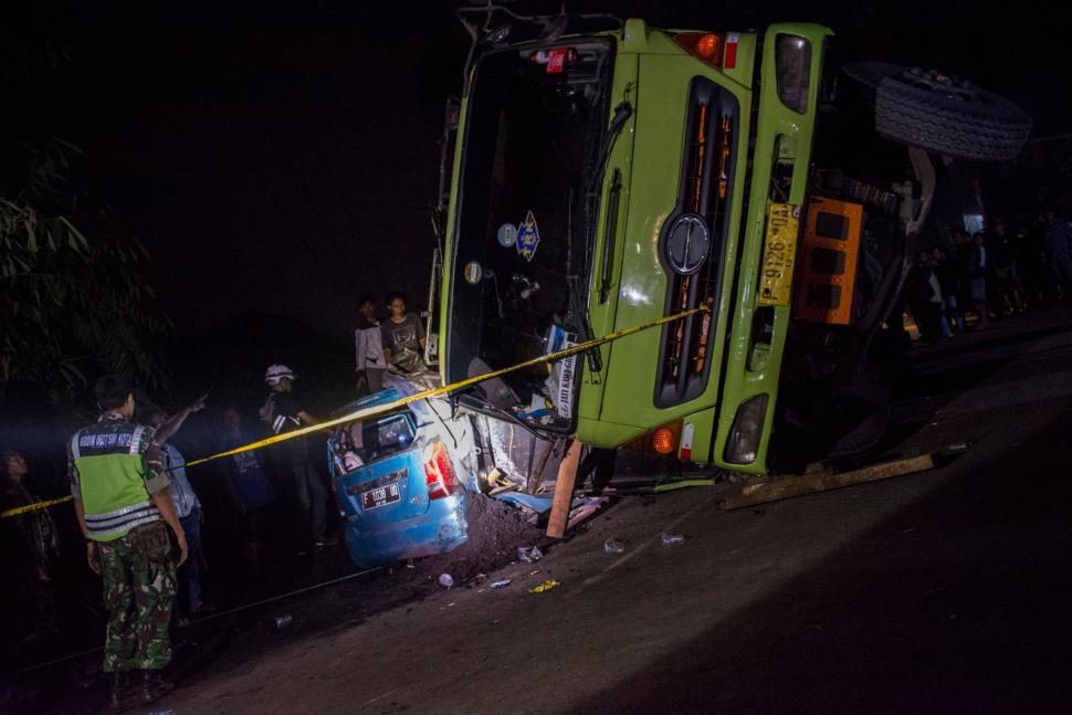 Sejumlah petugas dibantu warga berusaha mengeluarkan korban yang terjepit di dalam sebuah kendaraan minibus akibat tertimpa truk bermuatan batu bara di Jalan Raya Siliwangi, Parungkuda, Kabupaten Sukabumi, Jawa Barat, Sabtu (12/1). ANTARA FOTO/Nurul Ramadhan