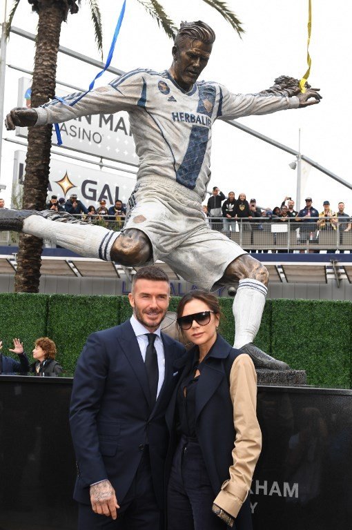 Mantan gelandang LA Galaxy David Beckham (kiri) dan istrinya, Victoria Bekcham berfoto disamping patung barunya di Legends Plaza, Carson, California. Mark RALSTON / AFP