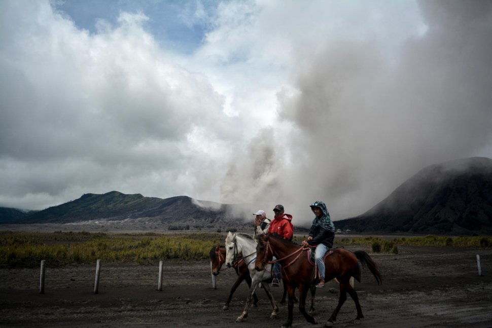 Tiga orang menunggang kuda dengan latar belakang Gunung Bromo yang menyemburkan abu vulkanis di Probolinggo, Jawa Timur, Jumat (15/3). ANTARA FOTO/Umarul Faruq