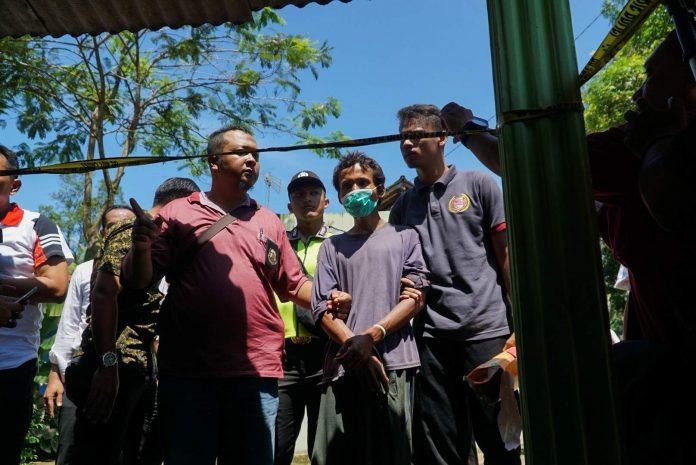 TERSANGKA perusakan tempat ibadah (menggunakan masker)dikawal petugas kepolisian saat melakukan pra rekontruksi di desa bumiayu kecamatan tambak Banyumas jumat (22/3). [SATELITPOST/Annang Firmansyah]