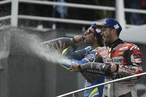 Pebalap Ducati, Andrea Dovizioso (kanan) merayakan keberhasilannya memenangi MotoGP Valencia bersama Alex Rins (Suzuki) yang finis kedua, Minggu (18/11/2018). [AFP/Jose Jordan]