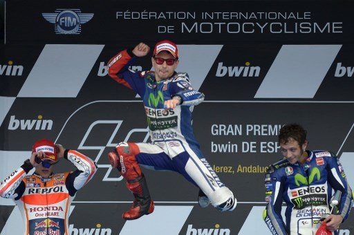 Jorge Lorenzo (tengah) meloncat kegirangan usai menjuarai MotoGP Spanyol 2015 di Sirkuit Jerez, Minggu (3/5). Diikuti kemudian oleh Marc Marquez (kiri) yang kini jadi rekan setimnya di Repsol Honda dan mantan partnernya di tim Movistar Yamaha, Valentino Rossi. [AFP/Jorge Guerrero]