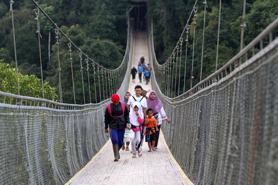 Wisatawan melintasi Jembatan Gantung Situ Gunung (Suspension Bridge Situ Gunung) di Kawasan Taman Nasioal Gunung Gede Pangrango (TNGGP), Kadudampit, Kabupaten Sukabumi, Jawa Barat, Jumat (25/5). [Suara.com/Arief Hermawan P]