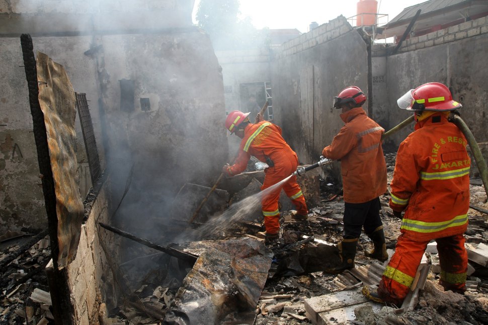 Petugas pemadam kebakaran (damkar) memadamkan sisa bara api usai terjadi kebakaran yang menghanguskan lapak pemulung di dekat Terminal Pasar Minggu, Jakarta, Sabtu (8/6). [Suara.com/Arief Hermawan P]