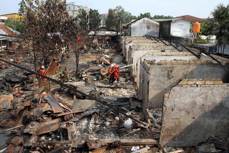 Petugas pemadam kebakaran (damkar) memadamkan sisa bara api usai terjadi kebakaran yang menghanguskan lapak pemulung di dekat Terminal Pasar Minggu, Jakarta, Sabtu (8/6). [Suara.com/Arief Hermawan P]