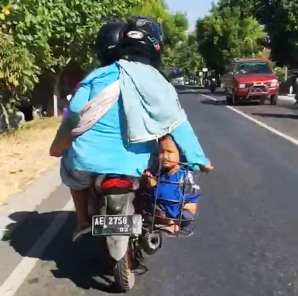 Mohammad Khoirul, warga Jalan Semen Remeng, Kelurahan Kertosari, Kecamatan Babadan, Ponorogo, yang membonceng anaknya dengan dimasukkan ke dalam keranjang besi dinilai berbahaya. (istimewa/viral)