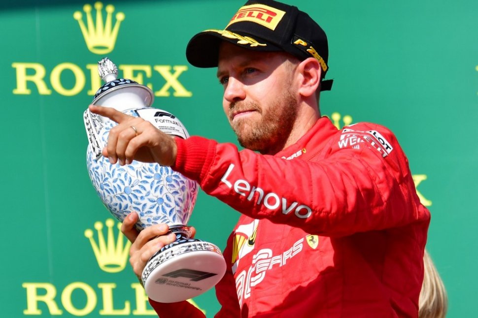 Pebalap Ferrari asal Jerman, Sebastian Vettel, merayakan keberhasilannya finis di podium ketiga balapan F1 GP Hungaria di Sirkuti Hungaroring, Minggu (4/8/2019). [AFP/Attila Kisbenedek]