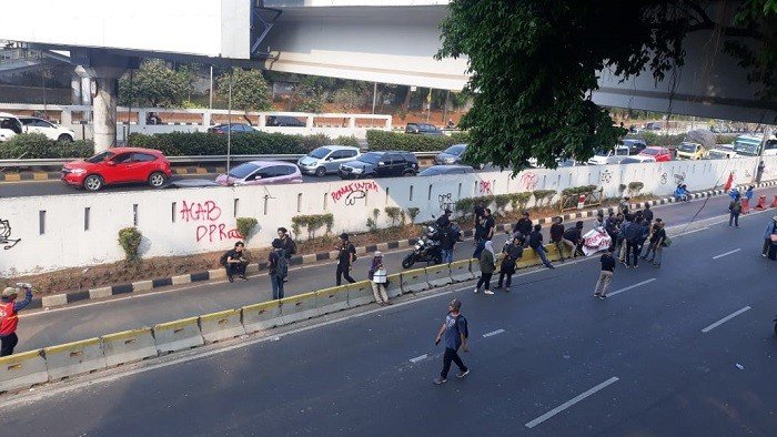 Aksi corat-coret para pendemo saat berunjuk rasa di depan gedung DPR RI. (Suara.com/Novian).