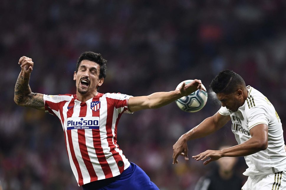 Bek Atletico Madrid Mario Hermoso dan gelandang Real Madrid Brasil Casemiro melompat untuk mendapatkan bola selama pertandingan sepak bola liga Spanyol antara Atletico Madrid melawan Real Madrid di stadion Wanda Metropolitano, Madrid, Spanyol, Minggu (29/9) dini hari WIB. [OSCAR DEL POZO / AFP]