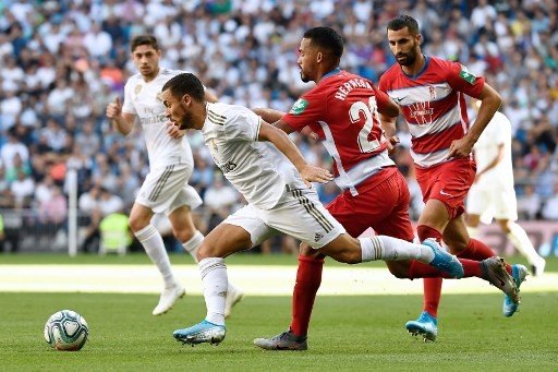 Pemain Real Madrid Eden Hazard menggiring bola sambil dibayangi pemain Granada, dalam laga di Santiago Bernabeu, Sabtu (5/10/2019) [AFP]