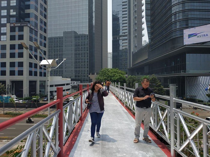 Pengguna JPO Sudirman - Thamrin, Jakarta Pusat, sebal terhadap Pemprov DKI yang mencopot atap fasilitas itu. Mereka mengatakan, lewat JPO itu saat siang hari terlampau panas. [Suara.com/Fakhri Fuadi Muflih]