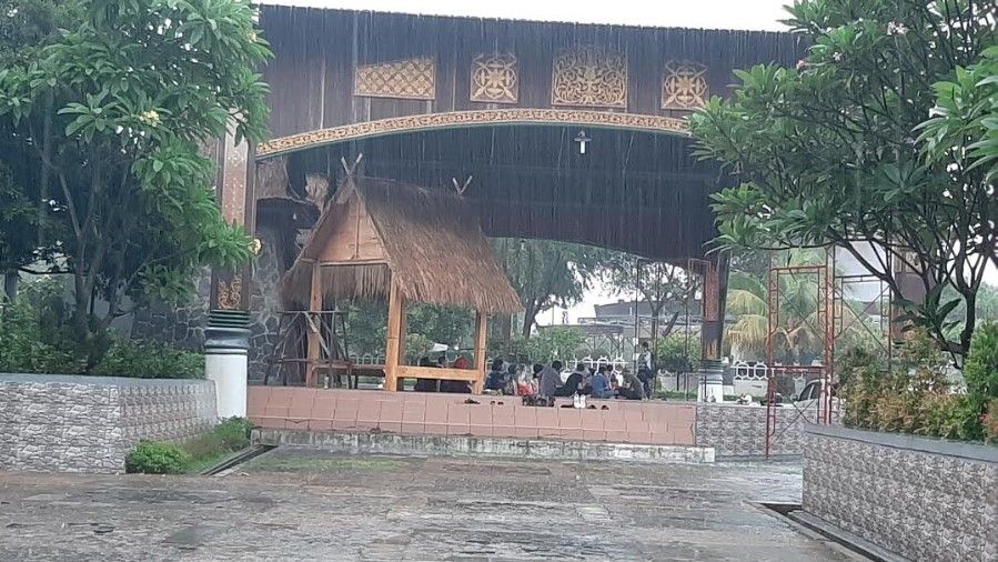 TMII Diguyur Hujan Jelang Malam Tahun Baru,  Pengunjung Berteduh di Anjungan. (Suara.com/Dini Afrianti Efendi)