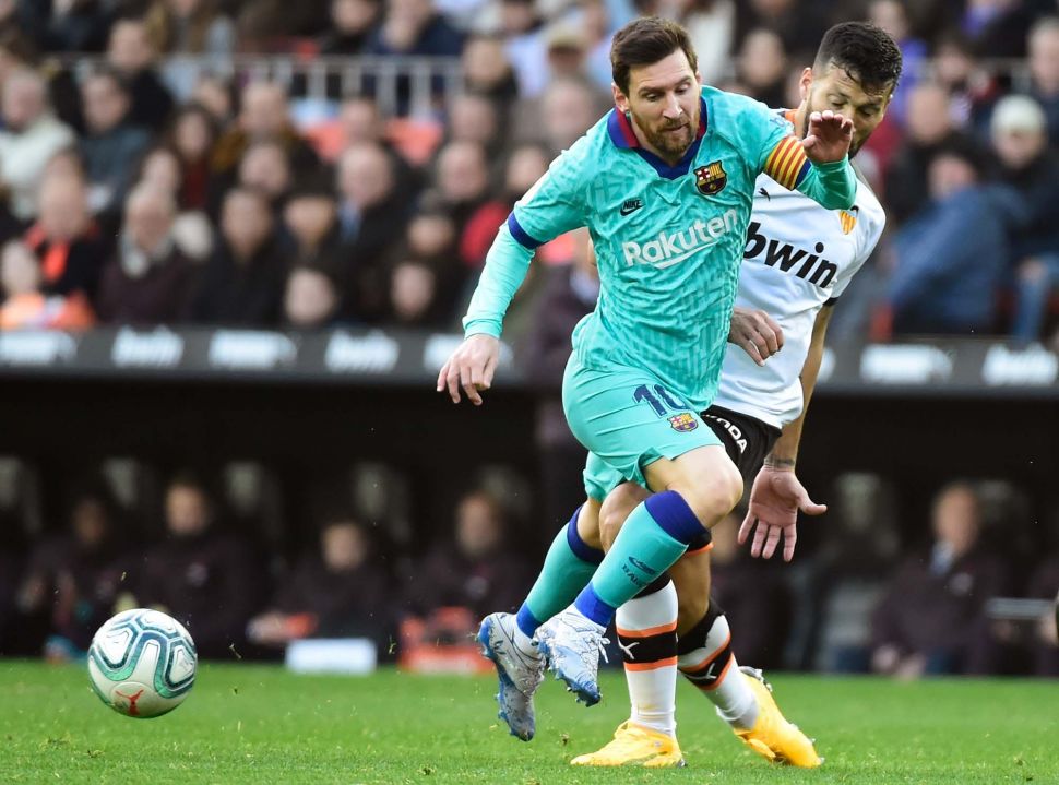 Bek Valencia Ezequiel Garay (kanan) menantang pemain depan Lionel Messi (kiri) selama pertandingan sepak bola liga Spanyol Valencia melawan Barcelona di Stadion Mestalla, Valencia, Spanyol, Sabtu (26/1).[JOSE JORDAN / AFP]