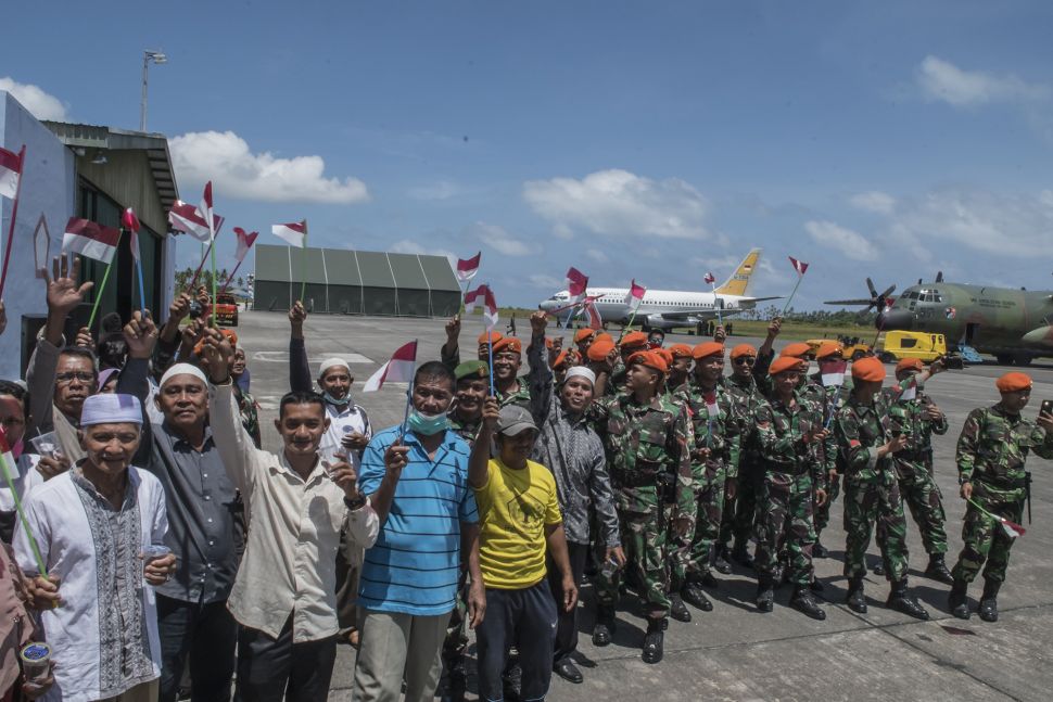 Sejumlah prajurit TNI bersama masyarakat mengibarkan bendera merah putih saat melepas Warga Negara Indonesia (WNI) yang telah selesai menjalani masa observasi usai dievakuasi dari Wuhan, Provinsi Hubei, China di Hanggar Pangkalan Udara TNI AU Raden Sadjad, Ranai, Natuna, Kepulauan Riau, Sabtu (15/2). [ANTARA FOTO/Muhammad Adimaja]