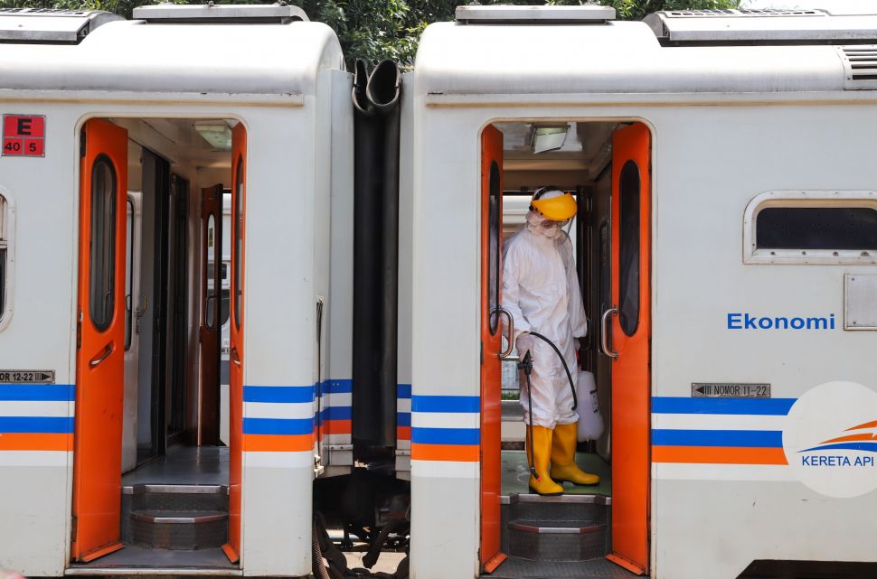 Petugas bersiap menyemprotkan cairan disinfektan di pintu gerbong kereta di Stasiun Pasar Senen, Jakarta, Minggu (15/3).[Suara.com/Alfian Winanto]