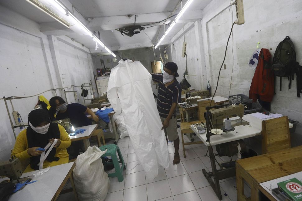 Pekerja menunjukkan pakaian untuk alat perlindungan diri tenaga medis di Pusat Industri Kecil, Penggilingan, Jakarta Timur, Rabu (24/3). [Suara.com/Angga Budhiyanto]
