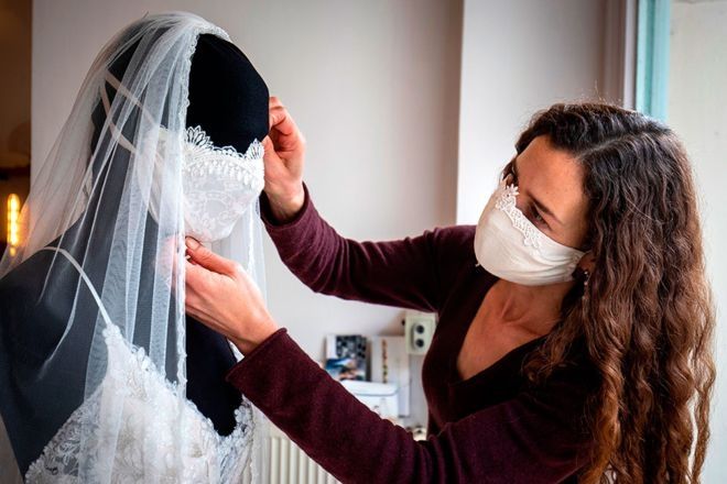 Desainer gaun pengantin dan pakaian malam Friederike Jorzig menyesuaikan manekin yang mengenakan gaun pengantin dengan masker yang serasi di tokonya, Chiton, di Berlin. Semua acara, termasuk pernikahan, telah dibatalkan di Jerman, sehingga perancang telah beralih ke membuat masker wajah modis di studionya. (ODD ANDERSEN / AFP)