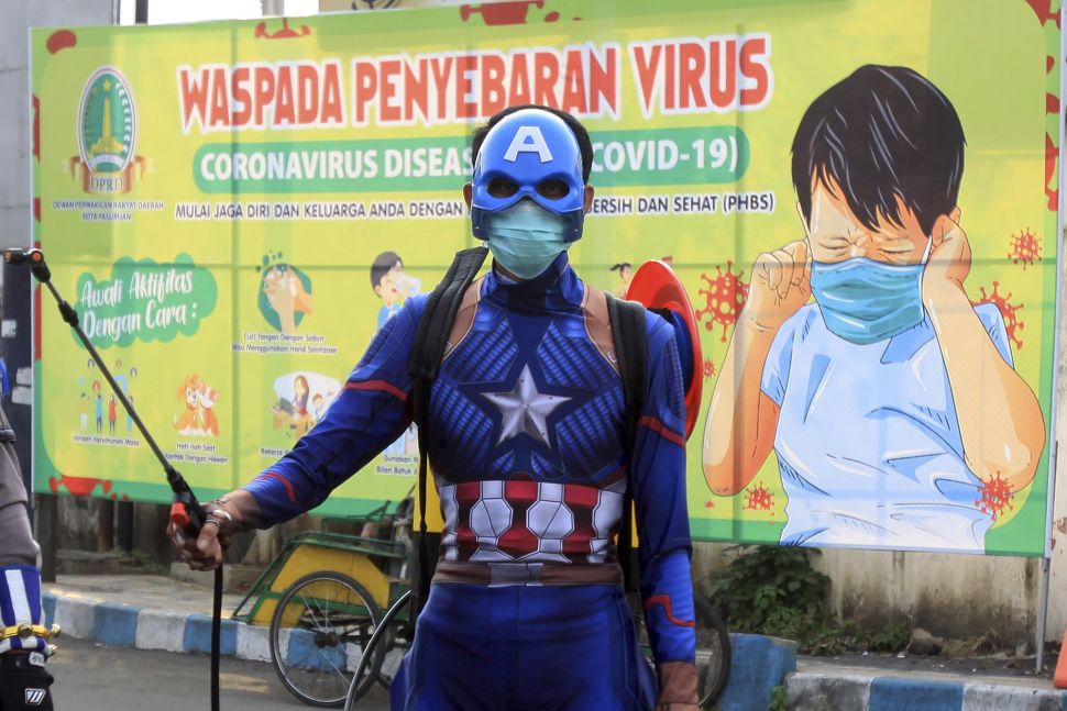 Petugas kepolisian berpakaian superhero menyemprotkan cairan disinfektan di Jalan Panglima Sudirman kawasan Kebonagung, Pasuruan, Jawa Timur, Kamis (9/4). [ANTARA FOTO/Umarul Faruq]