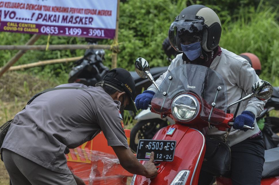 Petugas Gugus Tugas COVID-19 menempelkan stiker pada kendaraan bermotor di Perbatasan Tasikmalaya-Ciamis, Jembatan Cirahong, Kabupaten Ciamis, Jawa Barat, Jumat (10/4). [ANTARA FOTO/Adeng Bustomi]