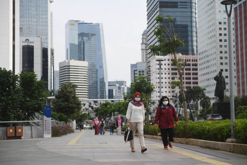 Sejumlah pekerja berjalan usai bekerja dengan latar belakang gedung perkantoran di Jl Jenderal Sudirman, Jakarta, Kamis (16/4).   [ANTARA FOTO/Akbar Nugroho Gumay]