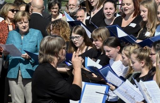 Kanselir Jerman Angela Merkel (kiri) bernyanyi bersama kelompok paduan suara mahasiswa di Berlin.[AFP]