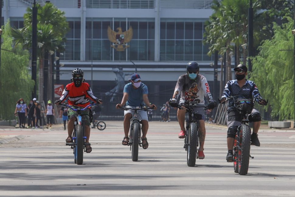 Warga berolahraga sepeda dengan menggunakan masker di Kompleks Olahraga Gelora Bung Karno, Jakarta Pusat, Minggu (31/5). [Suara.com/Alfian Winanto]