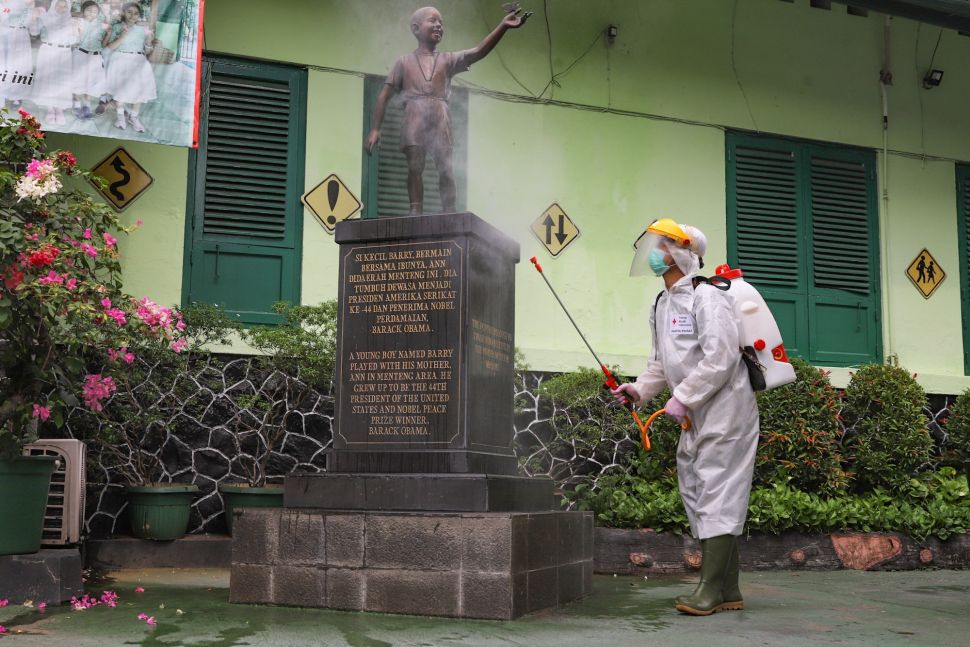 Petugas PMI menyemprotkan cairan disinfektan ke patung Barrack Obama di SDN 01 Menteng, Jakarta Pusat, Senin (15/1). [Suara.com/Alfian Winanto]