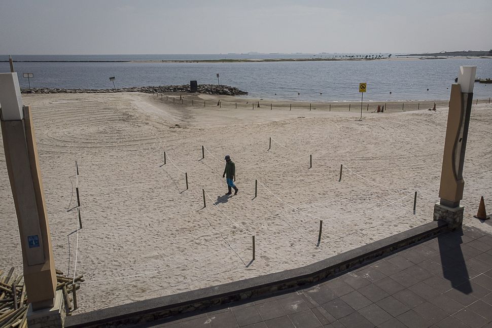 Pekerja berjalan di samping pagar pembatas yang digunakan untuk menjaga jarak pengunjung saat bermain di pantai Lagoon, Taman Impian Jaya Ancol, Jakarta, Rabu (17/6).  [ANTARA FOTO/Dhemas Reviyant]