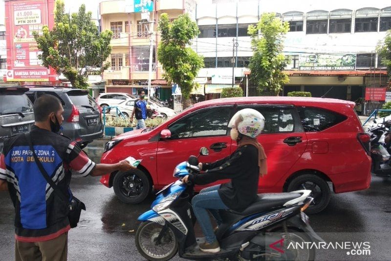 Salah satu juru parkir zona dua di Kota Bengkulu saat membagikan masker gratis kepada pengguna jalan raya sebagai bentuk kepedulian dalam masa pandemi COVID-19, Jumat (19/6/2020). (FOTO ANTARA/Carminanda)