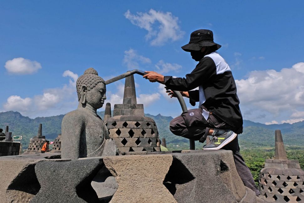 Petugas Balai Konservasi Borobudur (BKB) menyemprotkan air saat membersihkan abu vulkanik erupsi gunung Merapi di Candi Borobudur, Magelang, Jawa Tengah, Senin(22/6/2020).   [ANTARA FOTO/Anis Efizudin]