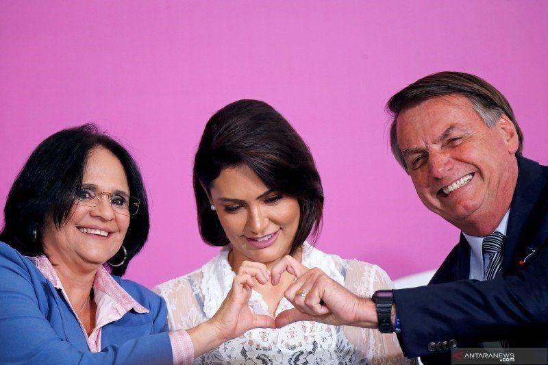 Presiden Jais Bolsonaro (kanan) dan istrinya, Michelle Bolsonaro (tengah), bersama Menteri Hak Asasi Manusia, Keluarga dan Perempuan Damares Alves membuat tanda hati saat peringatan Hari Perempuan Internasional di Istana Planalto di Brasillia, Brazil, Jumat (6/3/2020). (ANTARA/REUTERS/Adriano Machado/foc/djo) 