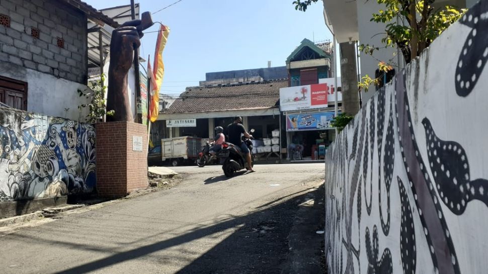 Salah satu sudut di kampung batik Manding Gunungkidul tampak dihiasi lukisan motif batik di dinding dan sebuah tugu berwujud tangan yang sedang memegang canting. [Kontributor / Julianto]