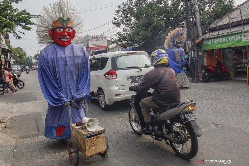 Pengamen Ondel-Ondel menari melintasi Jalan Raya Keadilan, Depok, Jawa Barat, Selasa (25/9/2019). [ANTARA/Yulius Satria Wijaya]