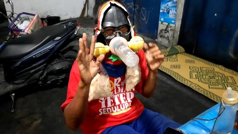 Ngadiran saat menunjukkan topeng berupa masker yang dia pakai sehari-hari saat berjalan dengan sepedanya ditemui di Jalan Godean, Sleman, Rabu (23/9/2020) malam. [Muhammad Ilham Baktora / SuaraJogja.id]