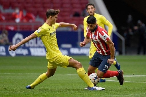 Pemain Atletico Madrid Luis Suarez berjibaku dengan pemain Villarreal dalam pertandingan La Liga di Estadio Wanda Metropolitano, Sabtu (3/10/2020). [AFP]