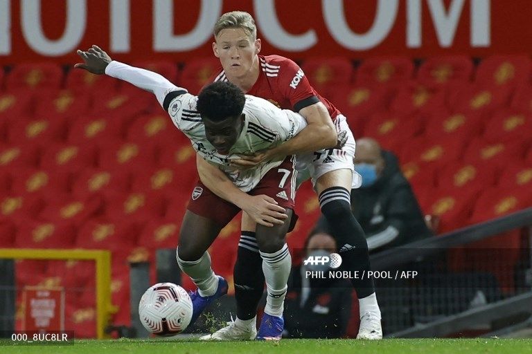 Gelandang Manchester United Scott McTominay (kanan) tengah memperebutkan bola dengan pemain Arsenal, Bukayo Saka dalam laga lanjutan Liga Inggris di Old Trafford, Manchester, Senin (2/11/2020) dini hari WIB. [PHIL NOBLE / POOL / AFP]