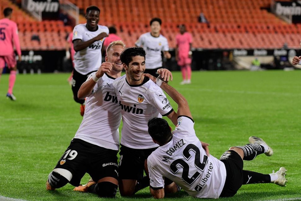 Gelandang  Valencia Carlos Soler (tengah) merayakan golnya bersama rekan satu timnya setelah mencetak gol ke gawang Real Madrid selama pertandingan sepak bola Liga Spanyol antara Valencia melawan Real Madrid di Stadion Mestalla, Valencia, Spanyol, Senin (9/11) dini hari WIB.  [JOSE JORDAN / AFP]