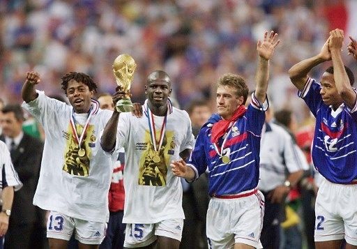 Lilian Thuram (kedua kiri) memegang trofi Piala Dunia usai Prancis mengalahkan Brasil di partai final di Stade de France pada 12 Juli 1998. [AFP]