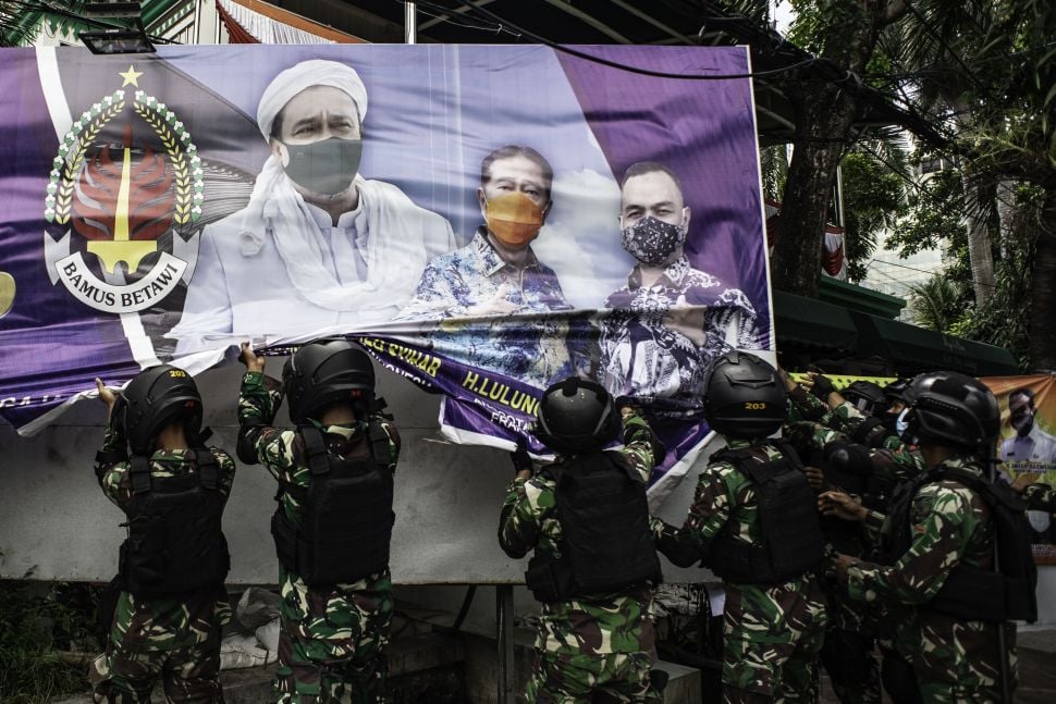 Prajurit TNI menurunkan spanduk bergambar Habib Rizieq Shihab saat patroli keamanan di Petamburan, Jakarta, Jumat (20/11/2020).  [ANTARA FOTO/Aprillio Akbar]