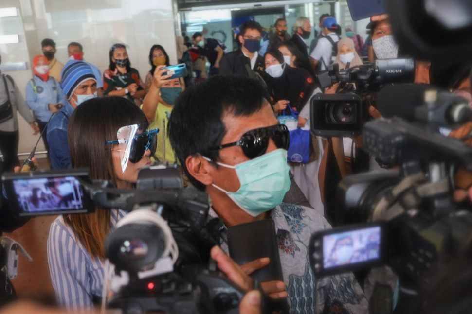 Komedia Kiwil bersama dengan istri mudanya, Eva Bellissima mencoba menghindari awak media saat tiba di Terminal 2 Bandara Soekarno Hatta, Tangerang, Banten, Rabu (16/12). [Suara.com/Alfian Winanto]