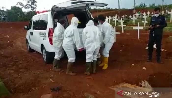 Petugas pemakaman pasien COVID-19 mengeluarkan peti jenazah dari dalam mobil ambulans untuk dimakamkan secara tumpang di blok muslim TPU Pondok Ranggon, Jakarta Timur, Minggu (27/12/2020). (ANTARA/HO-TPU Pondok Ranggon).