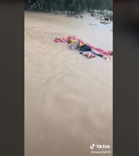 Video aksi pemuda rebahan di atas kasur saat banjir. (TikTok/mezzefah18)