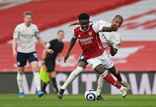 Pemain Manchester City Fernandinho menempel ketat pemain Arsenal Bukayo Saka dalam pertandingan Liga Premier yang berlangsung di Emirates Stadium, Minggu (21/2/2021). [AFP]