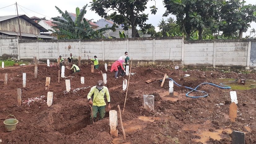 Para petugas penggali makam jenazah Covid-19 di TPU Bambu Apus, Jakarta Timur, Selasa (23/2/2021). [Suara.com/Yaumal]