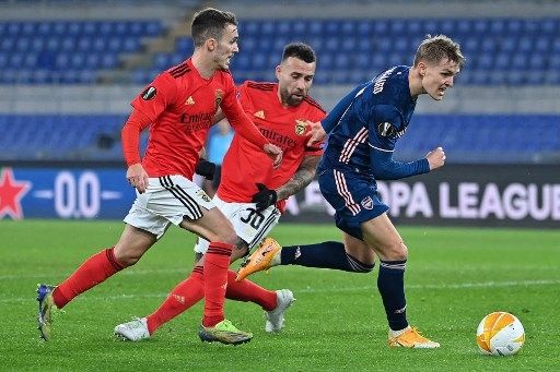 Pemain Arsenal Martin Odegaard berebut bola dengan pemain Benfica dalam pertandingan leg pertama babak 32 besar Liga Europa di Stadio Olimpico, Roma, 19 Februari 2021. [AFP]