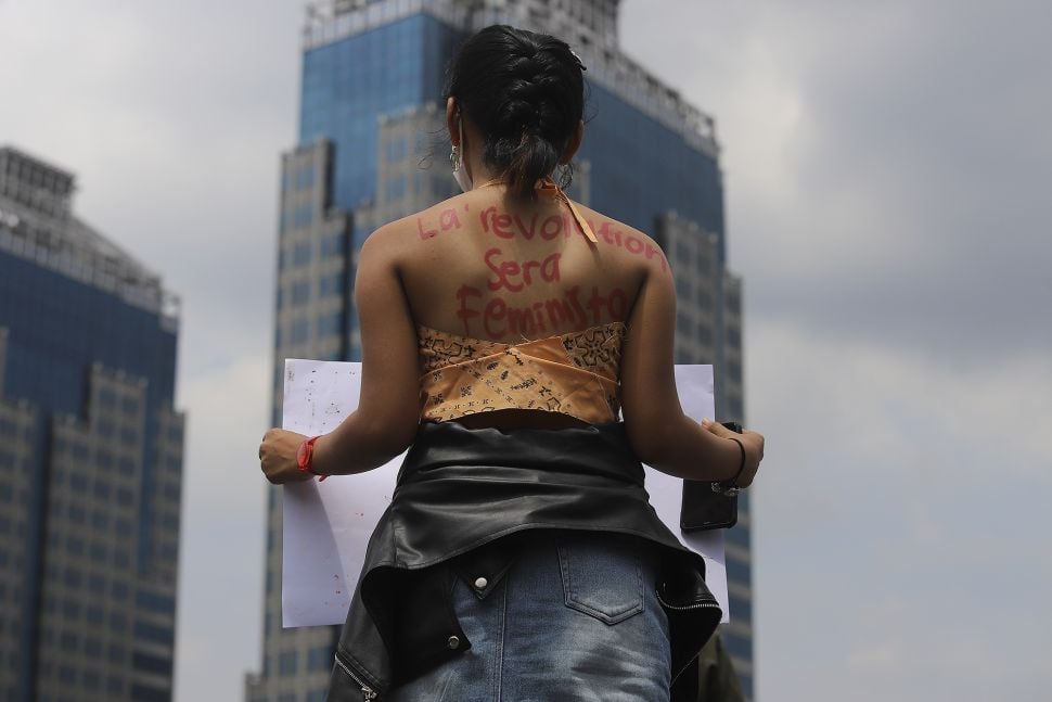 Tulisan di punggug seorang massa yang tergabung dalam Perempuan Mahardhika saat melakukan aksi memperingati Hari Perempuan Internasional di kawasan Patung Kuda Arjuna Wiwaha, Jakarta, Senin (8/3/2021). [Suara.com/Angga Budhiyanto]