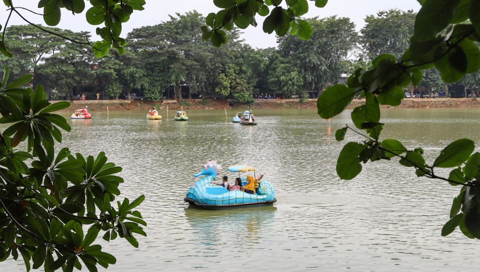 Warga menaiki wahana air saat berwisata di Perkampungan Budaya Betawi Setu Babakan, Jakarta Selatan, Minggu (4/4/2021). [Suara.com/Alfian Winanto]