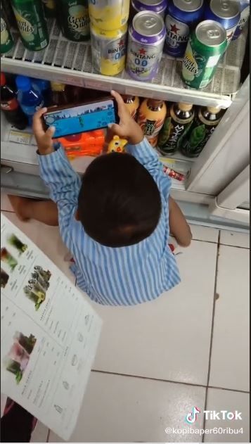 Anak kecil nongkrong di depan kulkas minuman mini market (TikTok @kopibaper60ribu4)