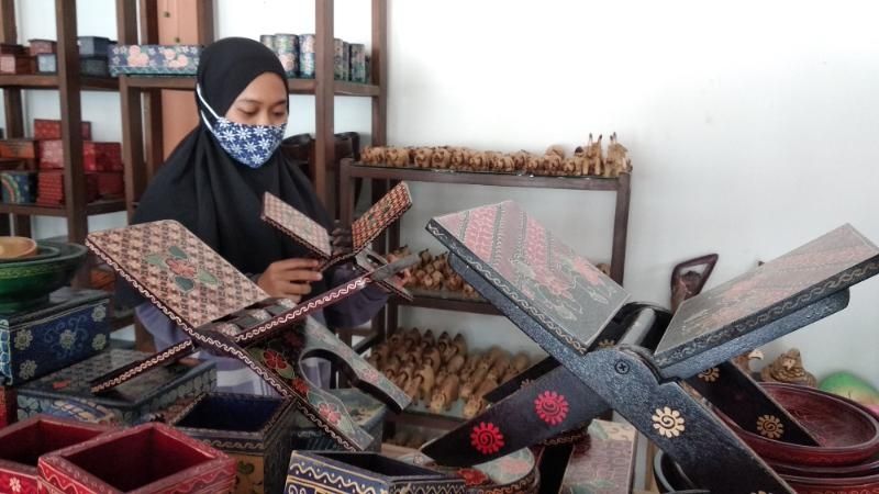 Salah seorang pembeli memilih motif batik ala Al Quran saat berada di Sanggar Peni, Padukuhan Krebet, Kalurahan Sendangsari, Kapanewon Pajangan, Bantul, Minggu (18/4/2021). [Muhammad Ilham Baktora / SuaraJogja.id]